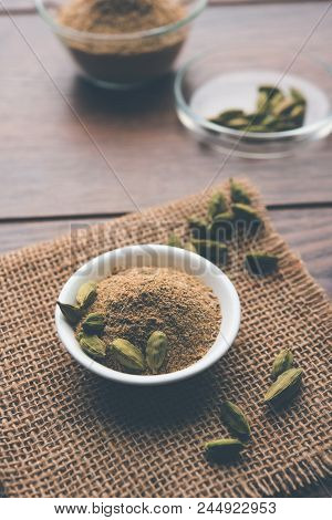 Elaichi Or Cardamom Powder In Bowl Or Heap Over Moody Background With Pods. Selective Focus