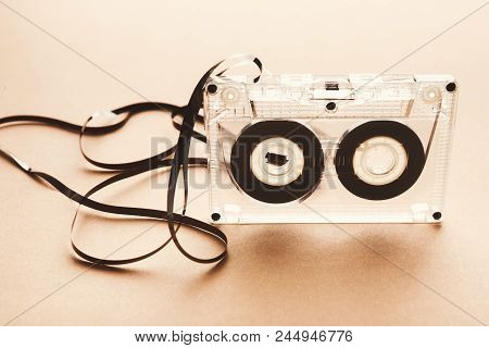 Old Audio Cassette With Unwound Tape On Beige Background. Top View On Broken Retro Multimedia Storag