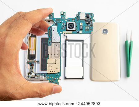 Close-up Of Technician Holdinging Smartphone Logic Boardon Blurred Smartphone Component Background