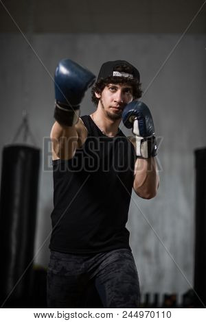 Muscular Young Boxer Training With Punching Bag