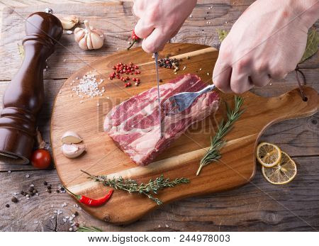 Hand Cutting Raw Beef Steak On Wooden Board