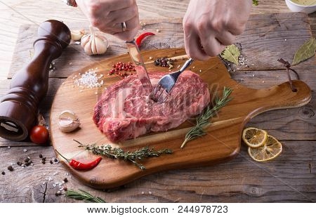 Hand Cutting Raw Beef Steak On Wooden Board