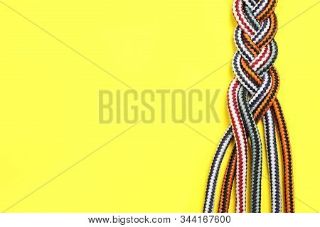 Top View Of Braided Colorful Ropes On Yellow Background, Space For Text. Unity Concept