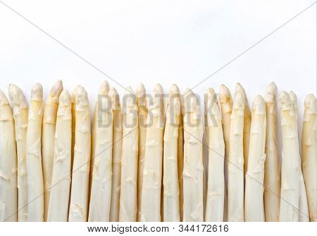Raw white Asparagus beaded in a row as close-up with copy space at top â isolated on white background 