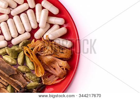 Ayurvedic Medicine Capsules, Cinnamon Sticks, Cloves, Cardamom And Mace Or Javitri In A Red Dish Pla