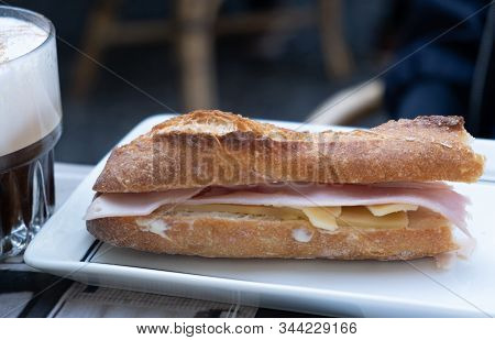 Fresh Sandwich With Ham And Cheese On White Dish Next To A Frappe Coffee. Blur Background.