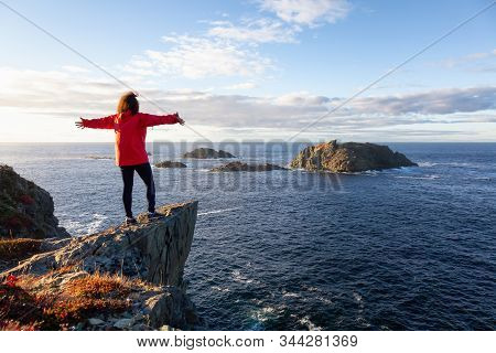 Woman In Red Jacket Is Standing At The Edge Of A Cliff With Open Arms And Enjoying The Beautiful Oce