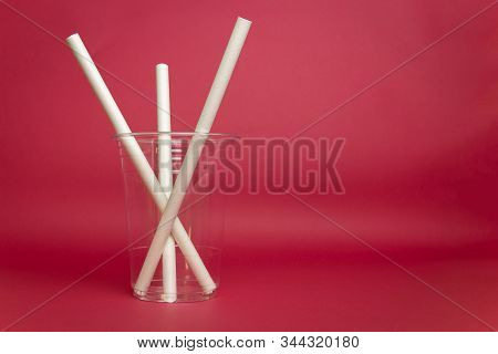 Empty Plastic Glss With Paper Straw Isolated In Red Background.