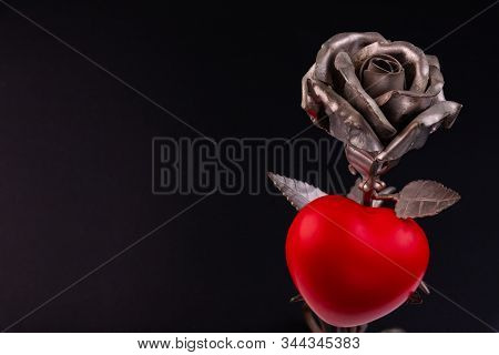 A Thin Bronze Rose Made By Forging From Metal. Red Volumetric Heart Nearby.