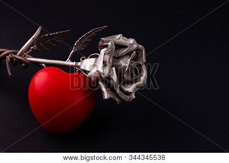 A Thin Bronze Rose Made By Forging From Metal. Red Volumetric Heart Nearby.