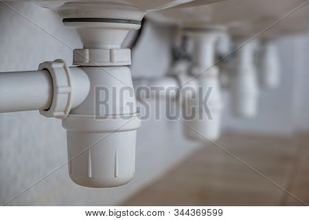 Close Up Of White Plastic Pipe Drain Under Washing Sink In Bathroom.