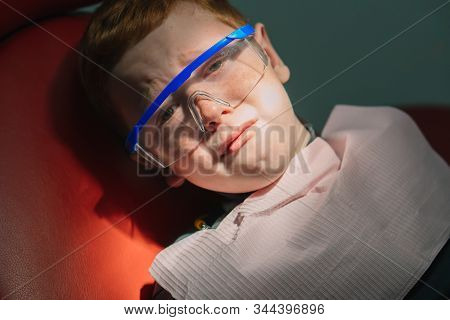 Scared Red-haired Boy Crying At Reception At Dentist In Dental Chair. Pediatric Dentistry