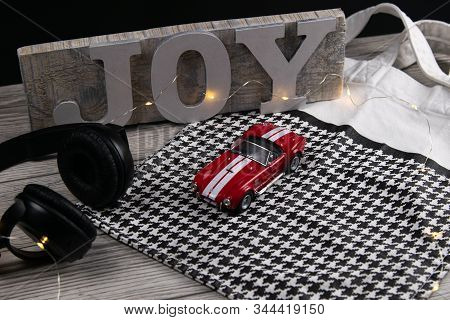 Toy Red Car On The On A Black White Checkered Bag Next To Headphones And In The Background A Plaque 