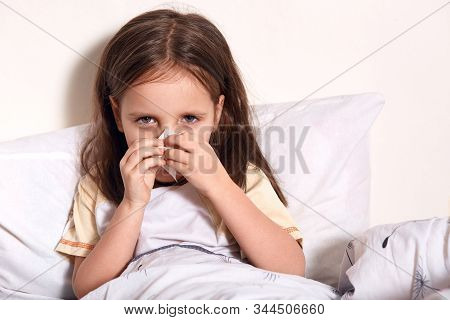 Dark Haired Gemale Using Some Napkins For Her Running Nose, Looking At Camera, Looks Sad And Upset, 