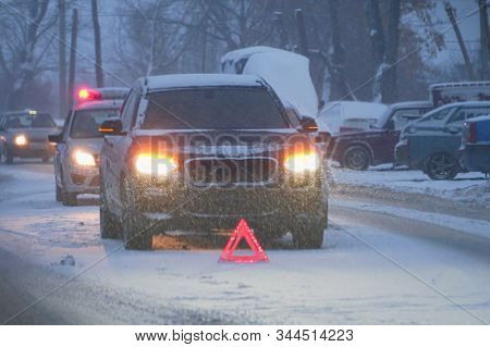 Emergency Sign In Front Of The Car On The Evening Winter Road