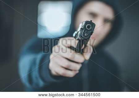 Crime Or Robbery Concept: Man With Black Gun Is Aiming With His Weapon