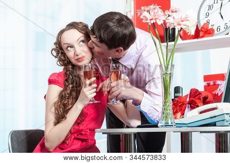 A Young Man, An Employee Of The Company Shows Courtship To His Colleague-a Young Woman With Curly Ha