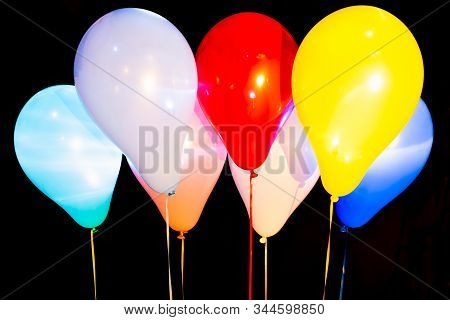 Colorful Helium Balloons Illuminated With Intern Led Light Against A Dark Background