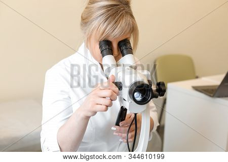 Female Blond Doctor Gynecologist Looks Through A Colposcope. Examination By A Gynecologist. Female H