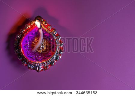 Burning Diya On Happy Diwali Purple Background For Light Festival Of India, Top View, Copy Space