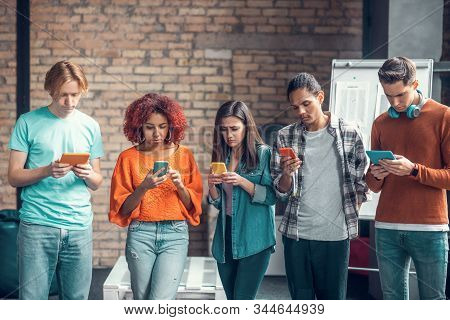 Students Addicted To Social Media Standing And Using Their Smartphones