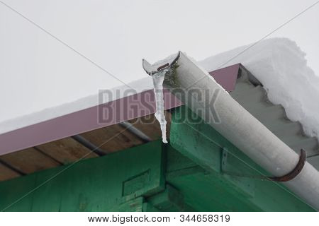 Icicle On The Drain Pipe Of A Wooden House