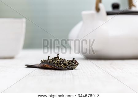 Green Tea In A Wooden Spoon Is On A Table In Front Of A Kettle And A Cup In A Tea Room.