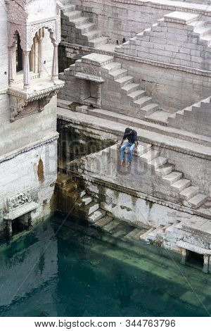 Jodhpur, India - December 8, 2019: A Man Sitting On The Steps Of The Stepwell Toorji Ka Jhalra In Th