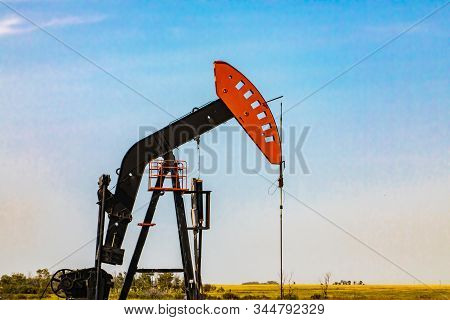 Closeup View Of A Pumpjack, Or Nodding Horse Head, Against A Pale Blue Sky With Copy Space. Orange A