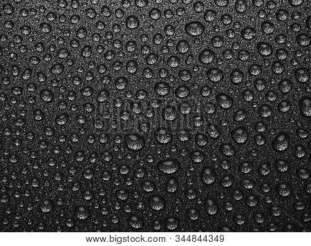 Abstract Background: Many Drops Of Water On A Dark Surface - Non-stick Coating In A Pan. Black And W