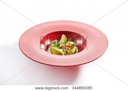 Gourmet salmon tartar with avocado puree, fresh parsley, lemon, spices on red restaurant plate. Macro shot of delicious luxury raw trout, tuna or yellowfin tatar closeup