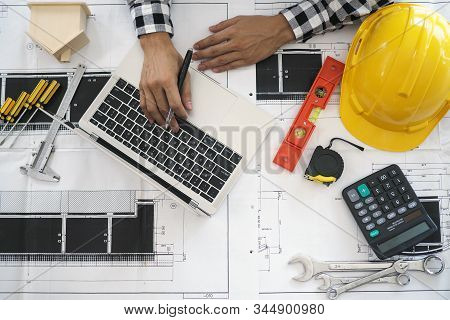 Engineers Work With Laptops And Blueprints. Calculate And Check The Construction Project.