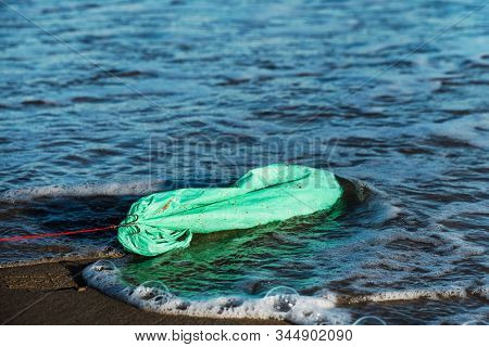 closeup of a used green plastic bag in a fish hook, freshly fished in the ocean