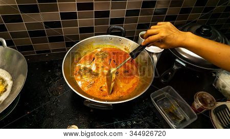 Hand Mixed Some Coconut Milk Into The Fish Head Curry In The Metal Wok Using Spatula.