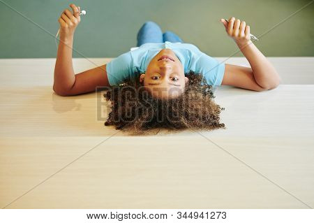Horizontal Top View Shot Of Pozitive Girl Of Mixed Race Relaxing In Modern Library Room Looking At C