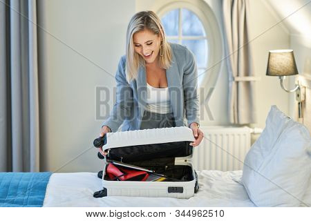 Businesswoman unpacking suitcase in hotel room