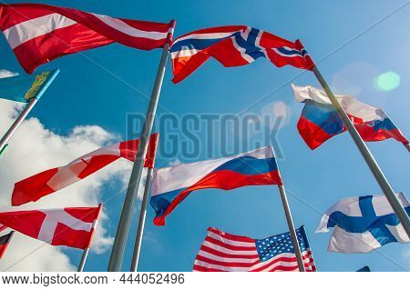 Bright Flags Of Different Countries Against The Blue Sky And Clouds