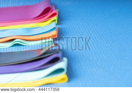 A Set Of Colorful Elastic Fitness Band. Expanders For Women And Weight Loss On A Blue Background Fla