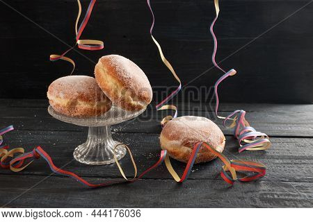 Berliner Doughnuts Or Krapfen With Colorful Party Streamers On A Dark Rustic Wooden Table, Tradition