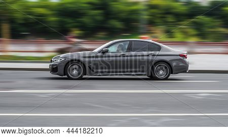 Bmw 530d Sedan G30 Post-facelift Driving On The City Street, Side View. Gray Car In Fast Motion On T