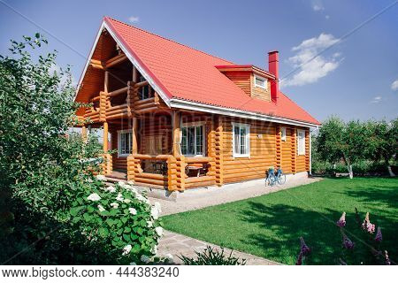 Large Wooden Newly Built Country House With Red Tile Roof, Lawn Area On Right And Cherry Trees Orcha