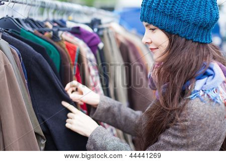 Femme en choisissant des vêtements au marché aux puces.