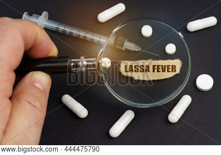 A Man Looks Through A Magnifying Glass At Pills, A Syringe And A Piece Of Paper With The Inscription