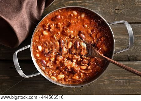 Stewed Beans With Ground Beef, Jalapeno Pepper And Bacon In Cooking Pan Over Wooden Background. Top 