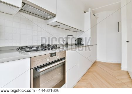 White Kitchen Set Windows In Sunlight. Minimalist Luxury Kitchen On Parquet Floor