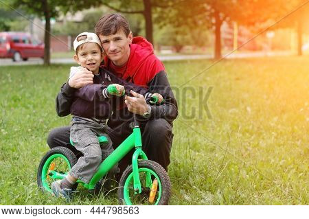 The Father Hugs A Little Son. Son And Father Rest After Father Taught His Son To Ride On A Balanced 