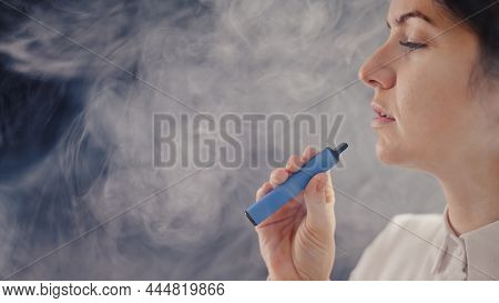 Caucasian Woman Smokes A Disposable Vape In The Studio.
