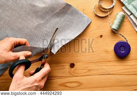 Woman Cutting Out A Pattern Paper In Linen Fabric. Seamstress Sewing On The Sewing Machine In Small 