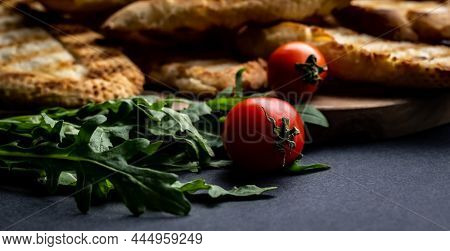 Cherry tomatoes, arugula and french baguette toasts closeup. Ingrediets for brueschettas snacks