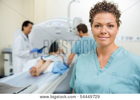Portrait of mid adult nurse with doctor and colleague preparing patient for CT scan in hospital